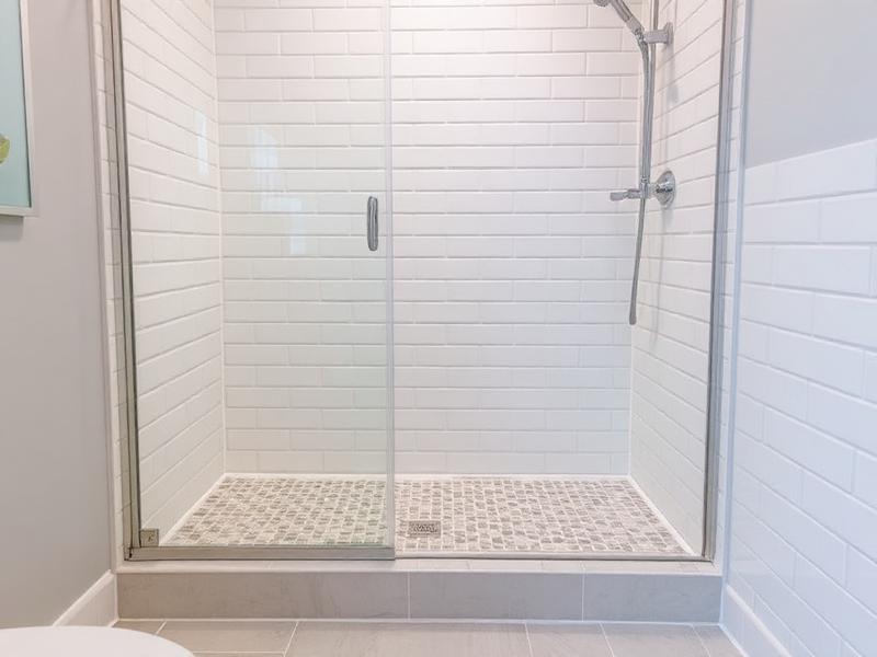 Modern bathroom shower with newly installed tiled shower pan and glass door